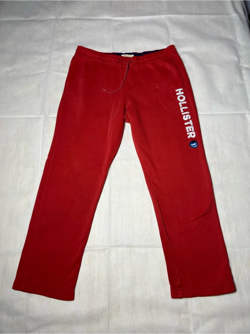 Hollister Co. red sweatpants with white vertical text reading 'HOLLISTER'